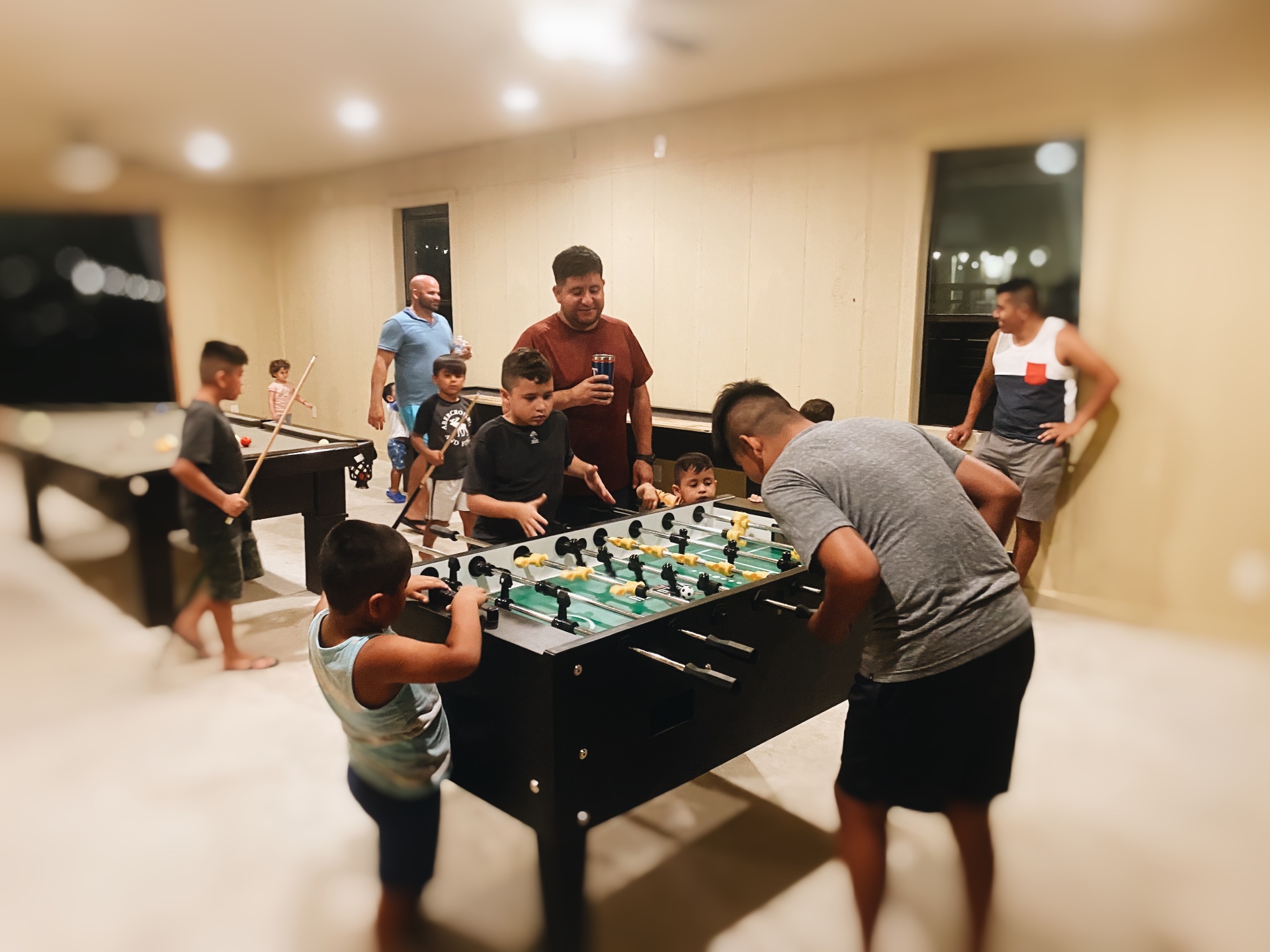 Family playing foosball and pool in the game room